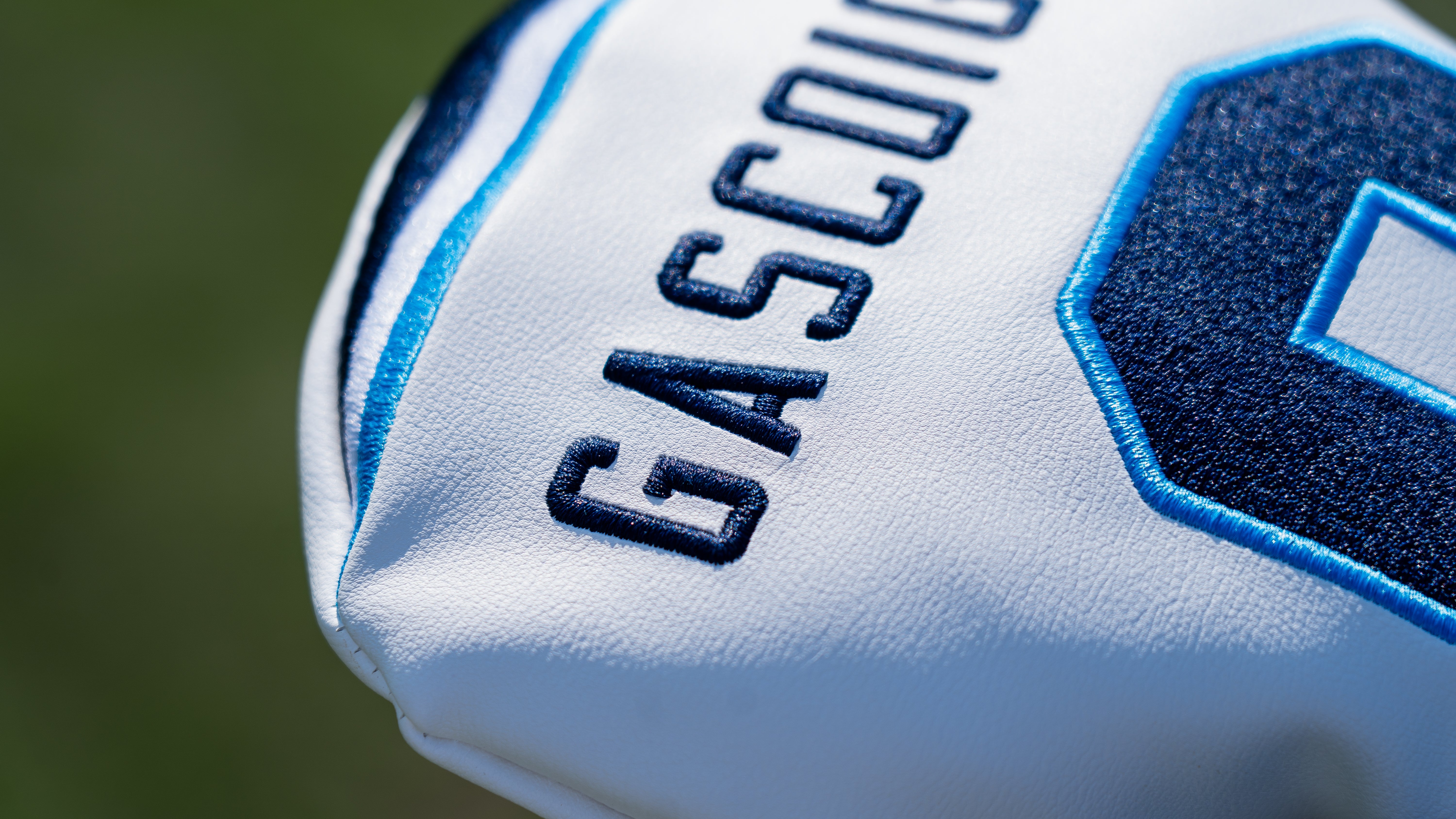 Close-up of a white golf club head cover with blue accents and 'Gascoigne' branding.